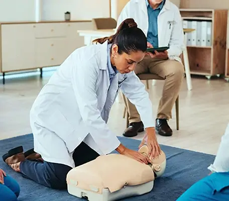 Instructor Demonstrating CPR on Dummy in ACLS Training Class