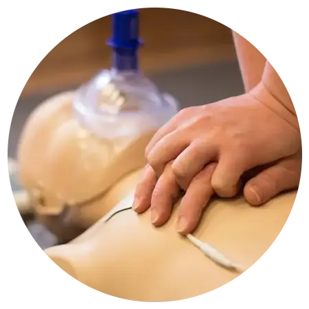 Hands Performing CP-R on a Manikin with Training Equipment Nearby