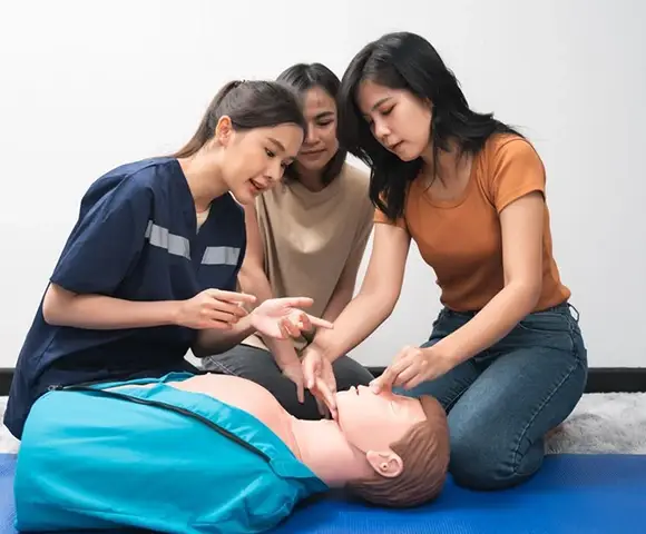 Three People Practicing CPR on Mannequin in CPR Training Session